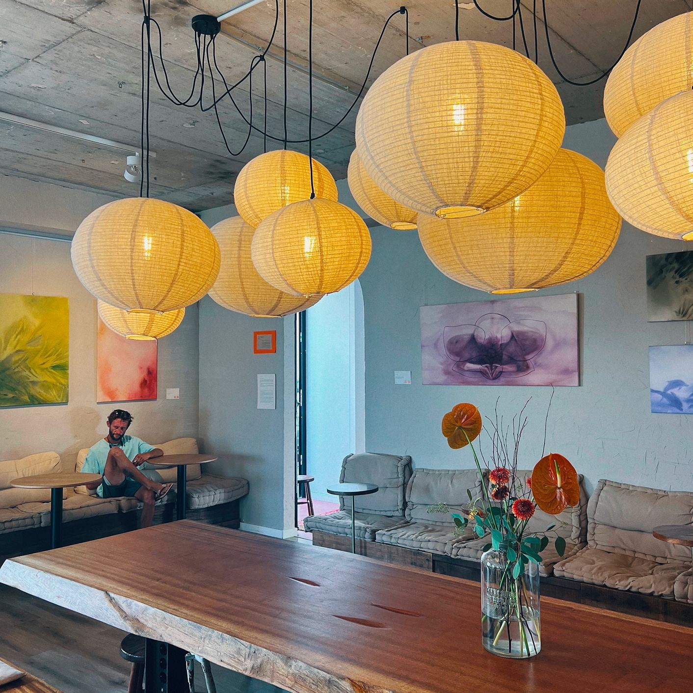 The paintings hung in a café under paper lanterns