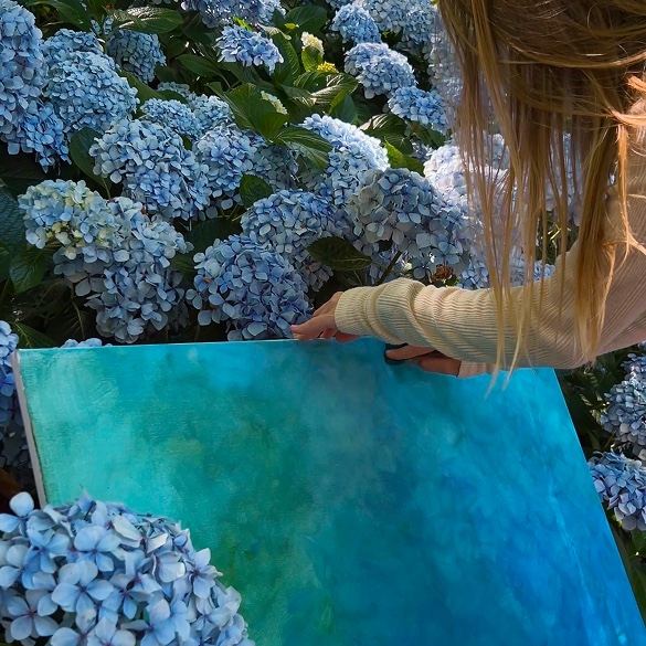 A blue canvas held among hydrangeas in bloom